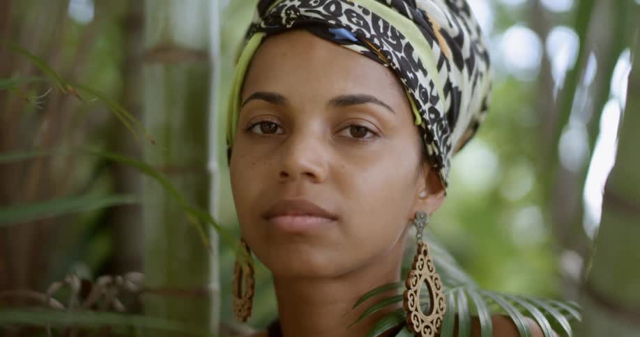 A woman standing and staring surrounded by plants