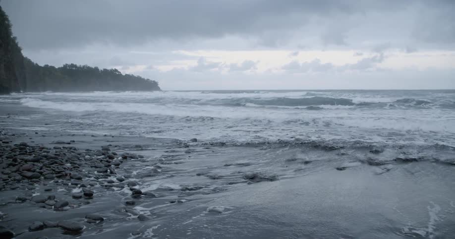 Coastal sea waves crash against the shore on a cloudy day