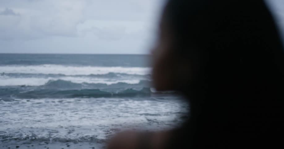A woman looks over her shoulder as she stands on the beach
