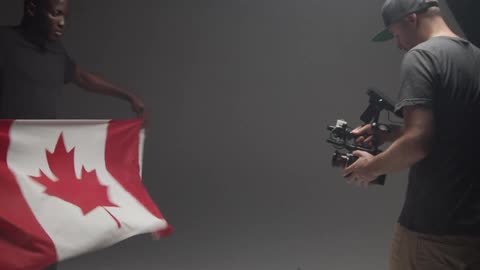 Person waving canadian flag as videographer shoots a video in a studio