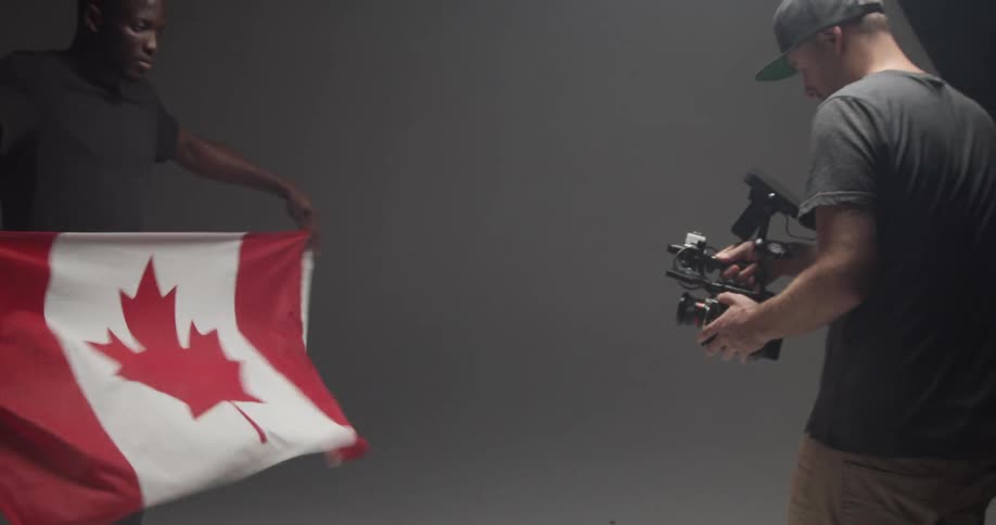 Person waving canadian flag as videographer shoots a video in a studio
