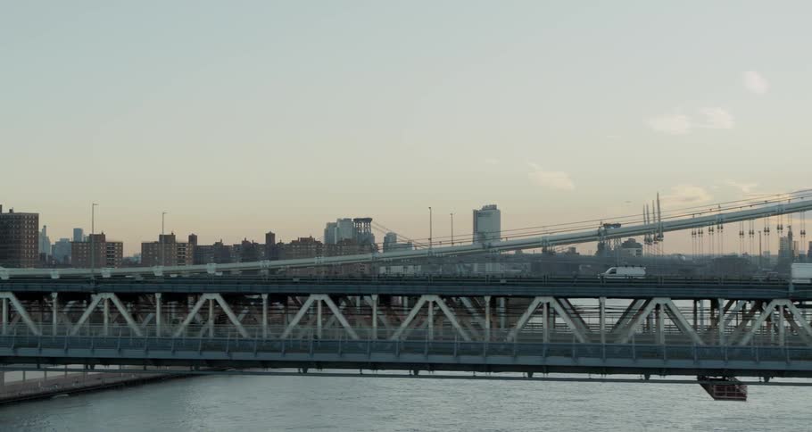 Vehicles travel a bridge over a river to a large city