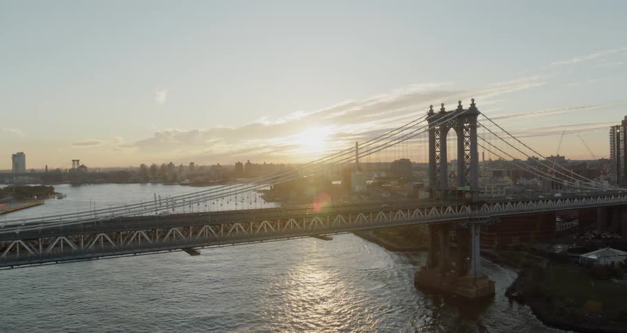 A suspension bridge carries traffic over a body of water that divides a metropolitan area