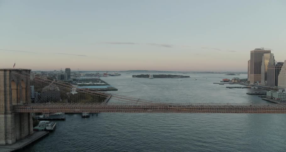 Cars travel across the brooklyn bridge as a boat passes underneath