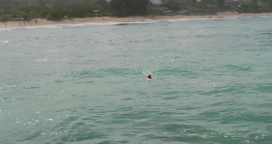 A person swims on a surfboard in the ocean water