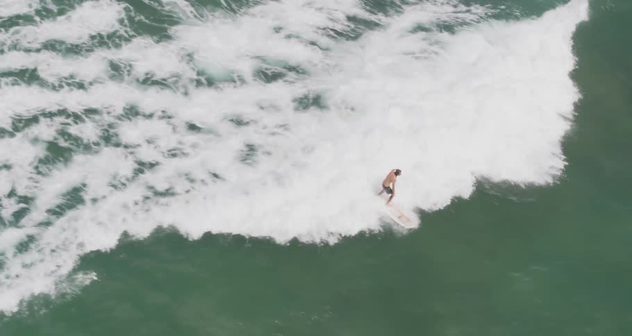 A man is surfing as a wave white caps behind him