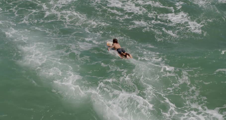 A man is wading in the water on a surfboard