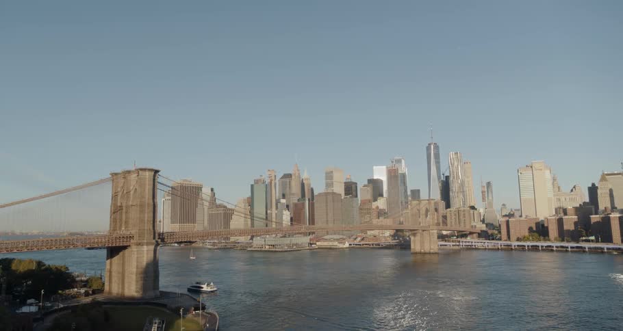 A bridge over a body of water leads to downtown with numerous skyscrapers