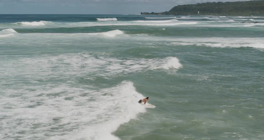 Aerial of a surfer catching and surfing a wave in the ocean