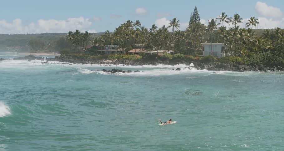 A person floats on a surfboard with big waves coming to them