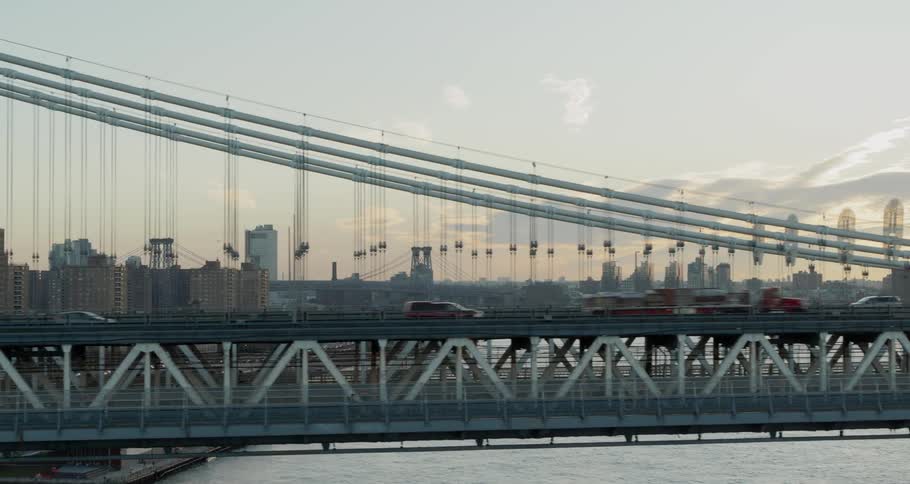 Vehicles cross the brooklyn bridge with horizontal and diagonal suspender cables in new york city in the late afternoon