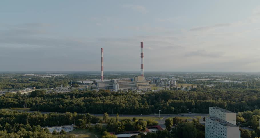 Red and white stacks on top of a factory in an urban neighbourhood
