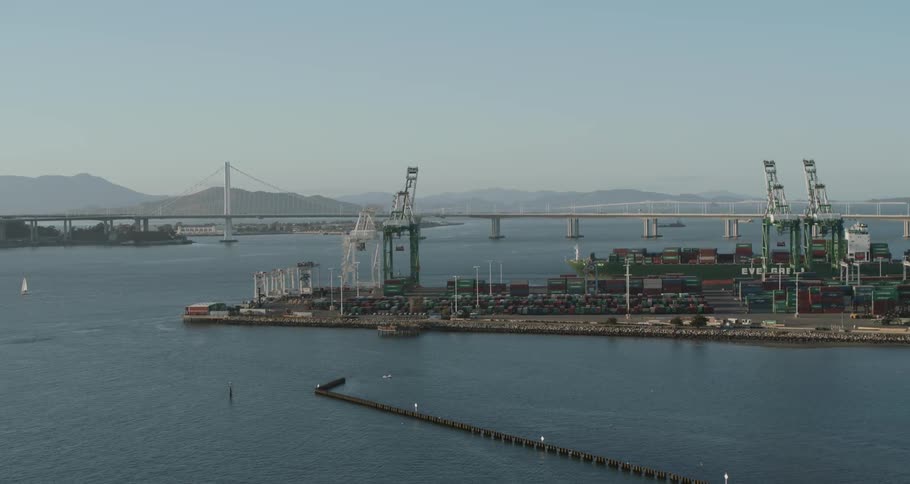 A shipping dock with shipping containers and a bridge in the background