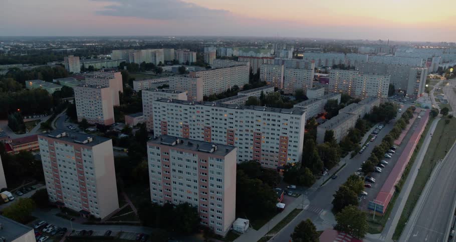 Tall apartment buildings border smaller buildings and the highway at sunrise