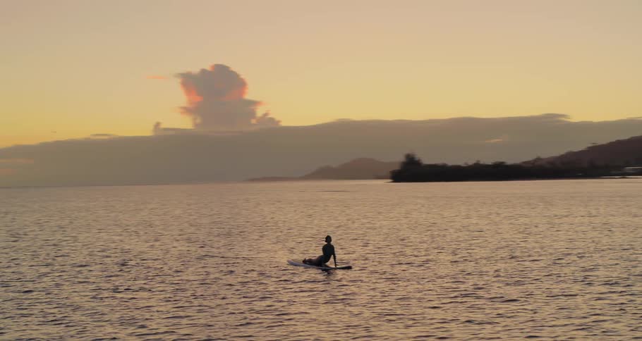 A person sits on a surfboard far into the ocean water