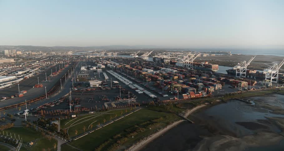 A shipping container port with large parking lots near a city