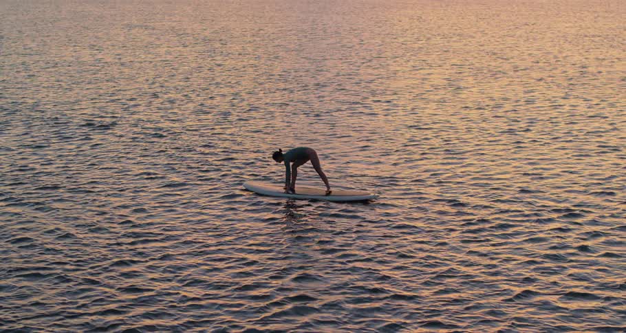 A woman falls from the surfboard into the ocean