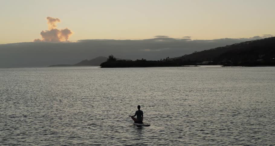 A silhouette of a man meditate on the middle of a lake