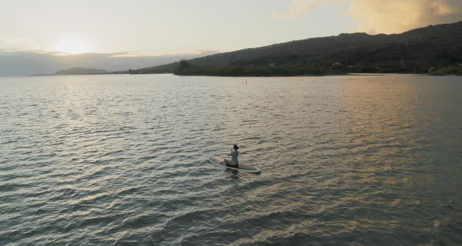 A woman is meditating on the surfboard