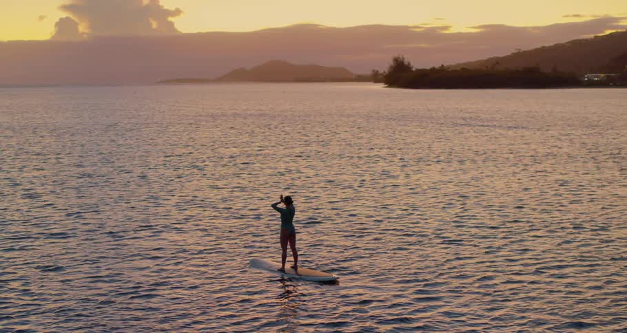 A woman standing on a surfboard on the ocean