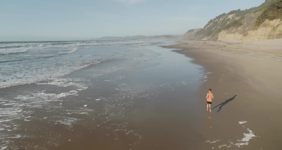 Man running on the sand along the shoreline in a bay