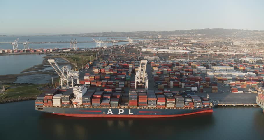 Shipping containers are stacked upon each other at a shipping port along the shore