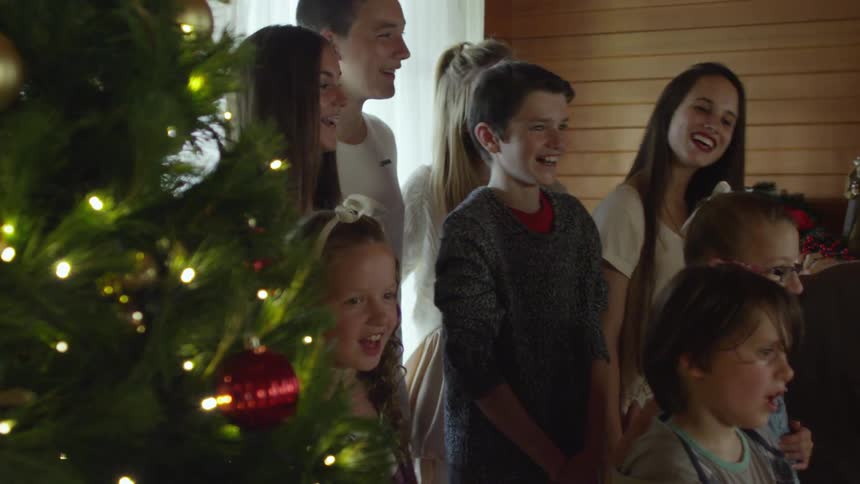 Younger members of a large family are singing and smiling at a christmas celebration