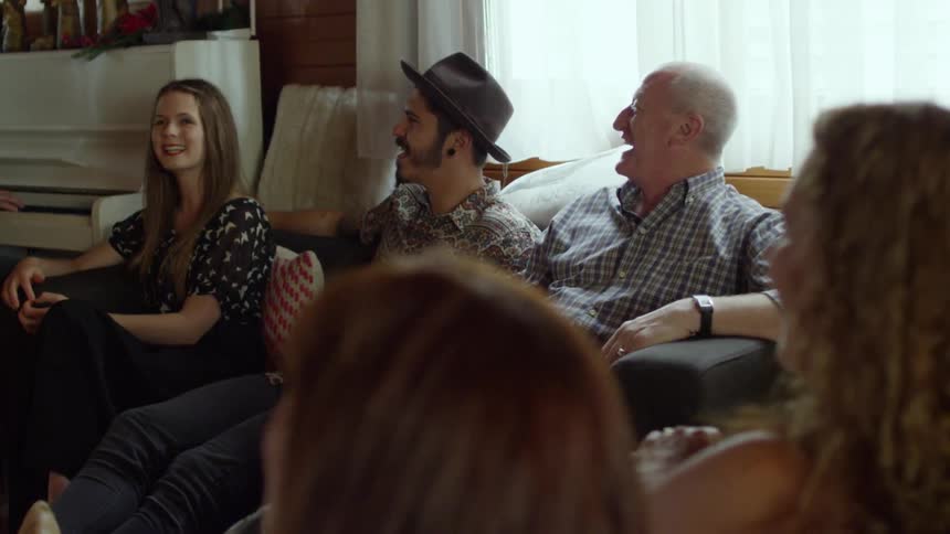 A group of people sit in a room singing and laughing