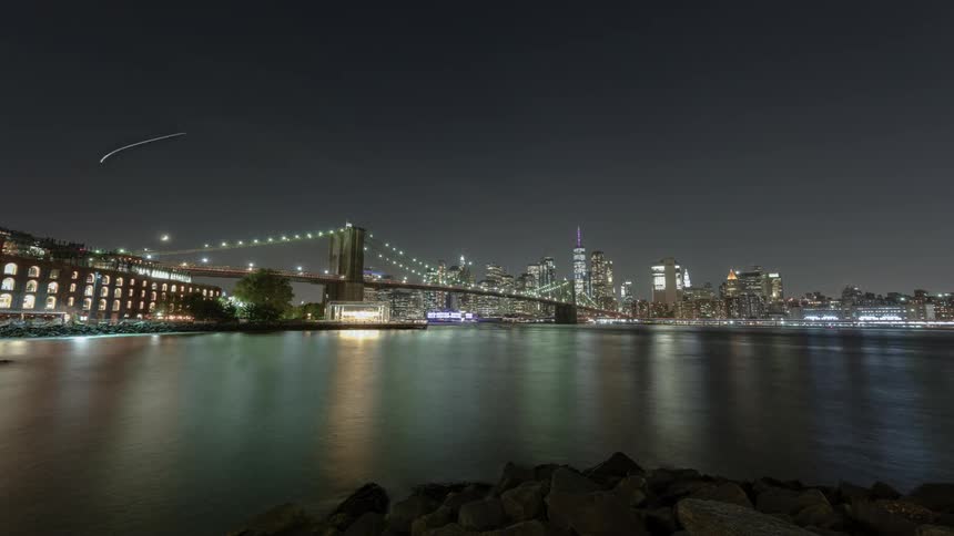 A river at night with a bridge and the city skyline in the background