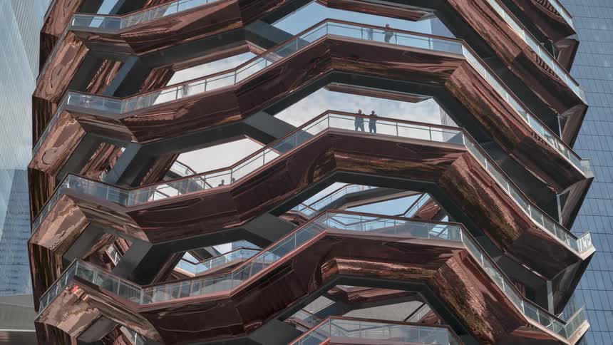 People walk around a giant set of high rise stairs in a city
