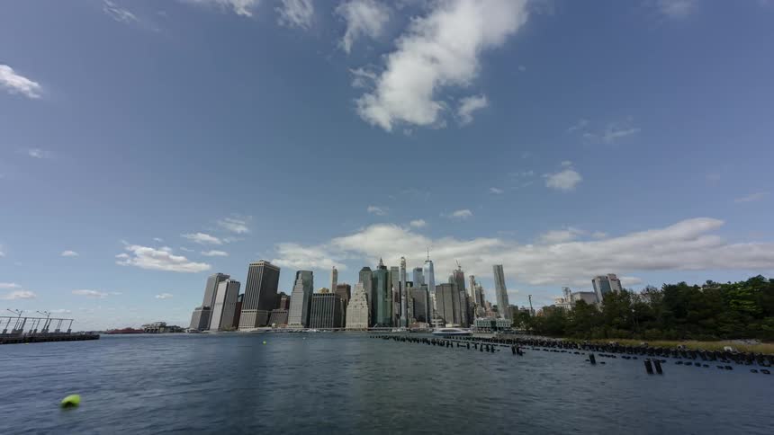Clouds float over a city bay and tall skyscrapers on a summer day