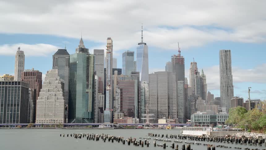 Boats move by large buildings in a major city