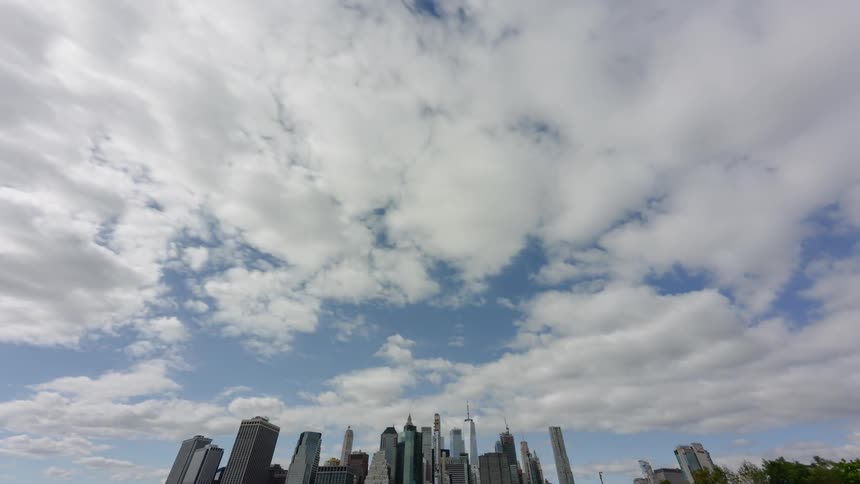 Clouds morph and move over a large city next to water