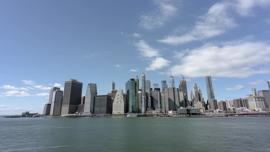 Boats speed across water as clouds flow over downtown skyscrapers