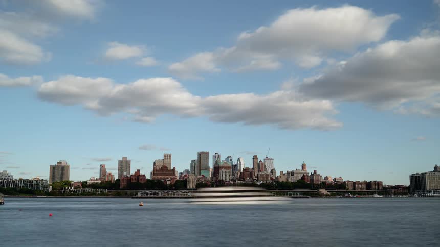 Boats driving in the water outside of a large city skyline