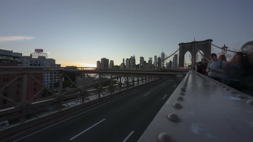 Pedestrians pause at walkway overlooking highway and leading to suspension bridge