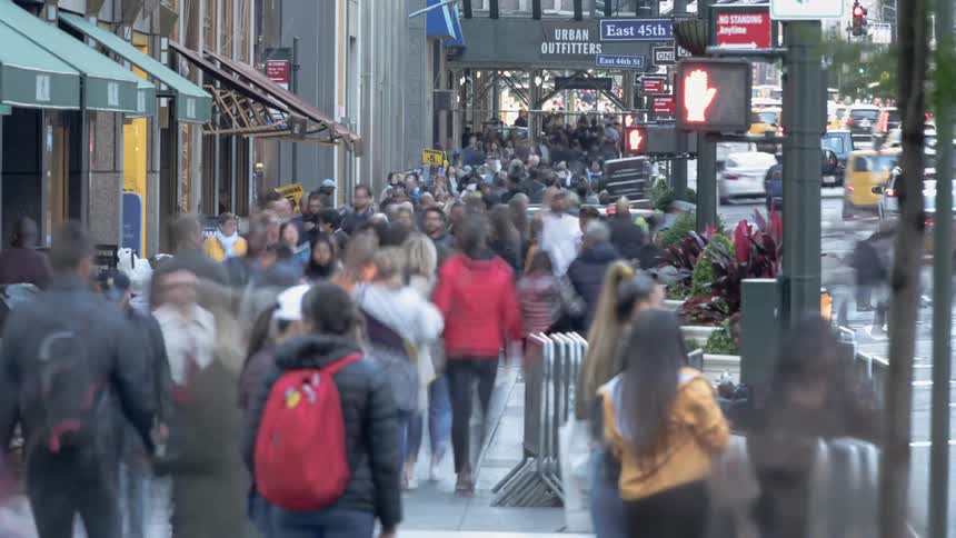 A city sidewalk is crowded with pedestrians