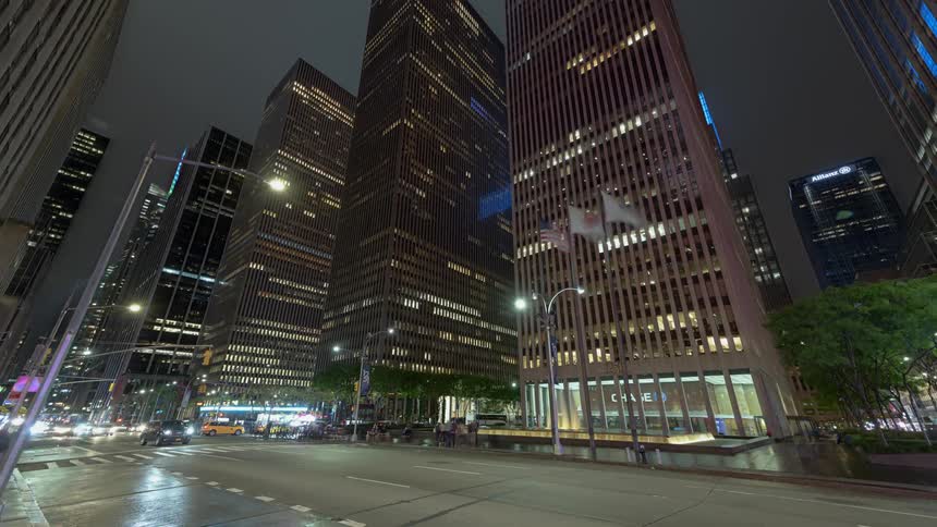 Traffic passes along street among skyscrapers at night