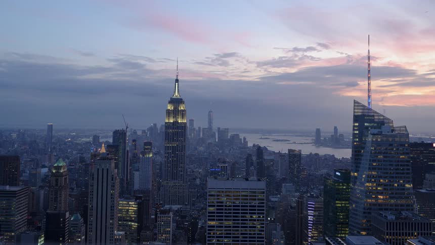 Clouds pass over city and river as night falls