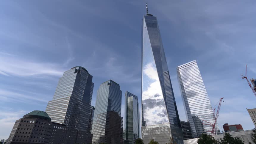 Passing clouds reflect off the sides of tall skyscrapers