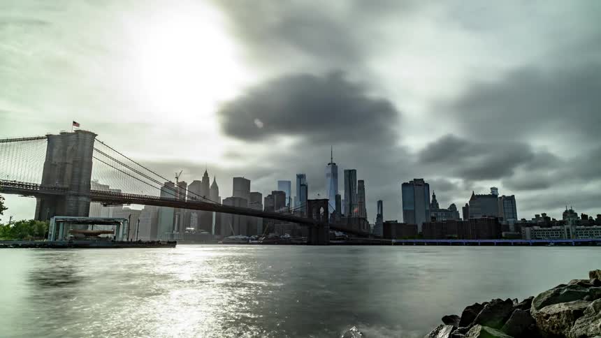 Clouds move over the river next to a city