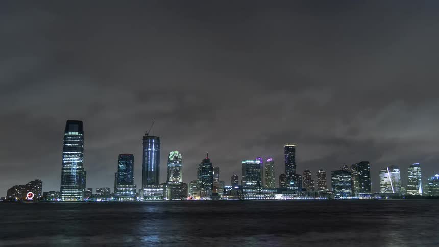 A city at night sits by a large body of water