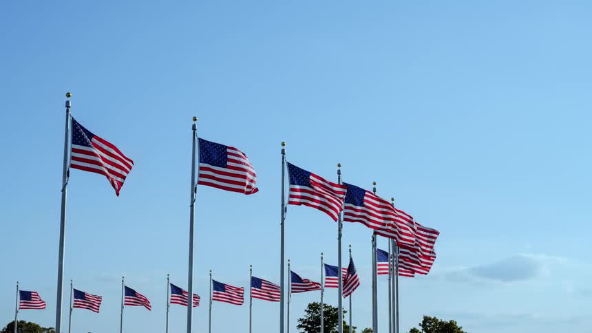 American flags flapping in the wind with the sky in the background