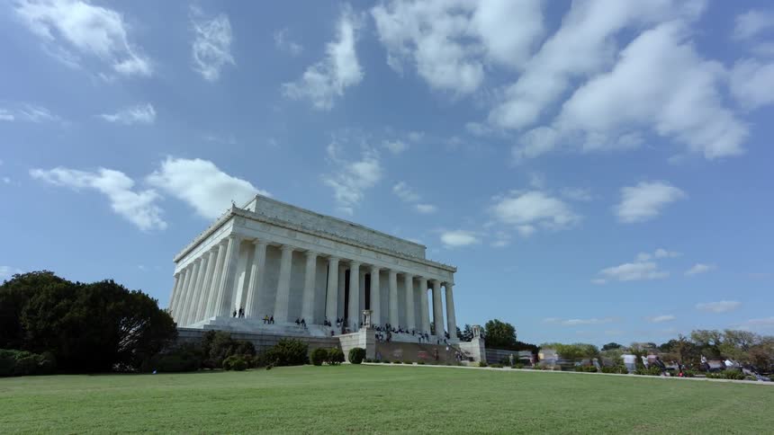 People stream in and out of the lincoln memorial on a blue sky day