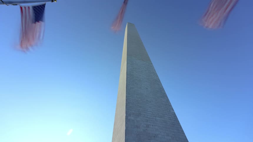 A series of american flags encircle a pyramidal monument