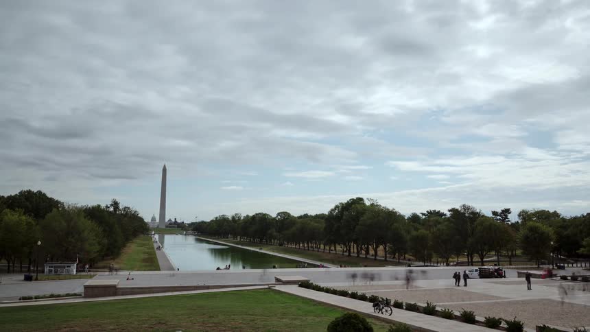 Tourists walking along the sidewalks and viewing a monument