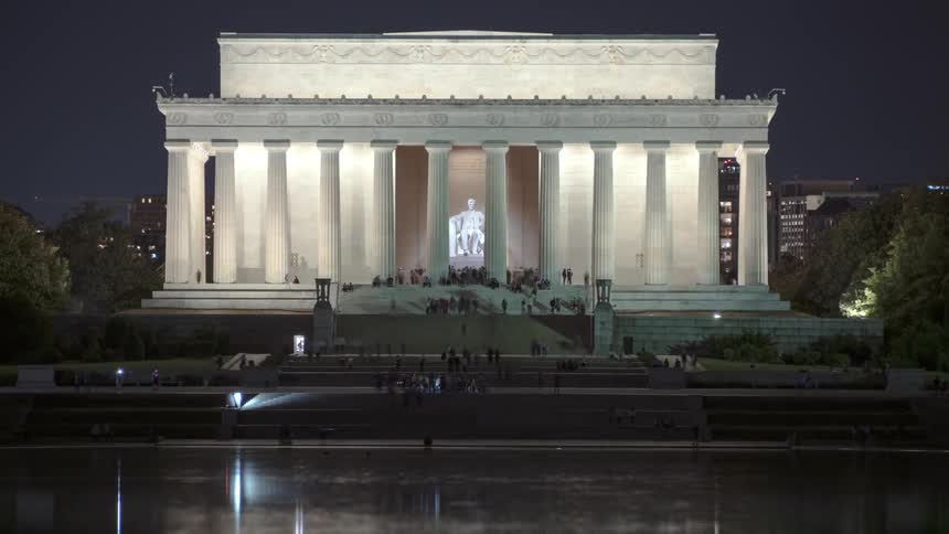 People walk up and down the steps of the lincoln memorial at night