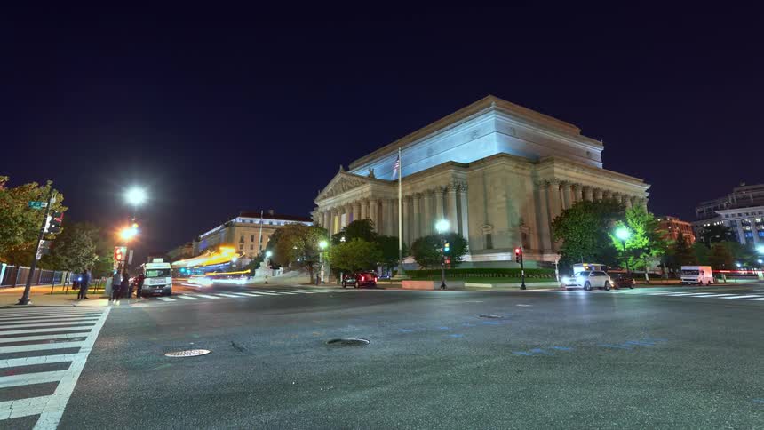 Traffic passes through an intersection in front of a government building