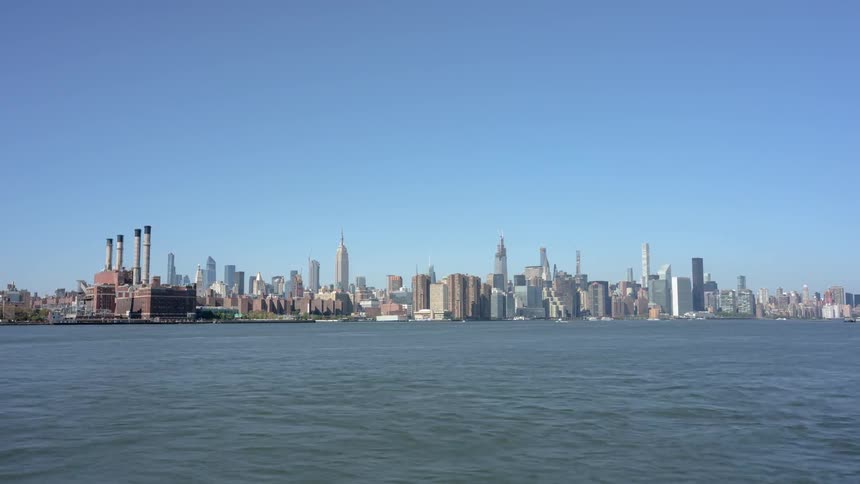 A large city sits next to a body of water with lots of boats