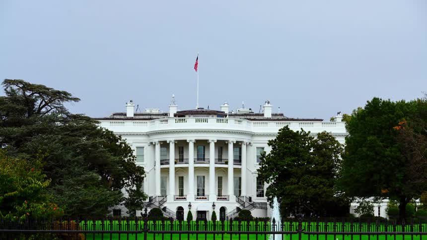 An american flag blows in the wind above the white house